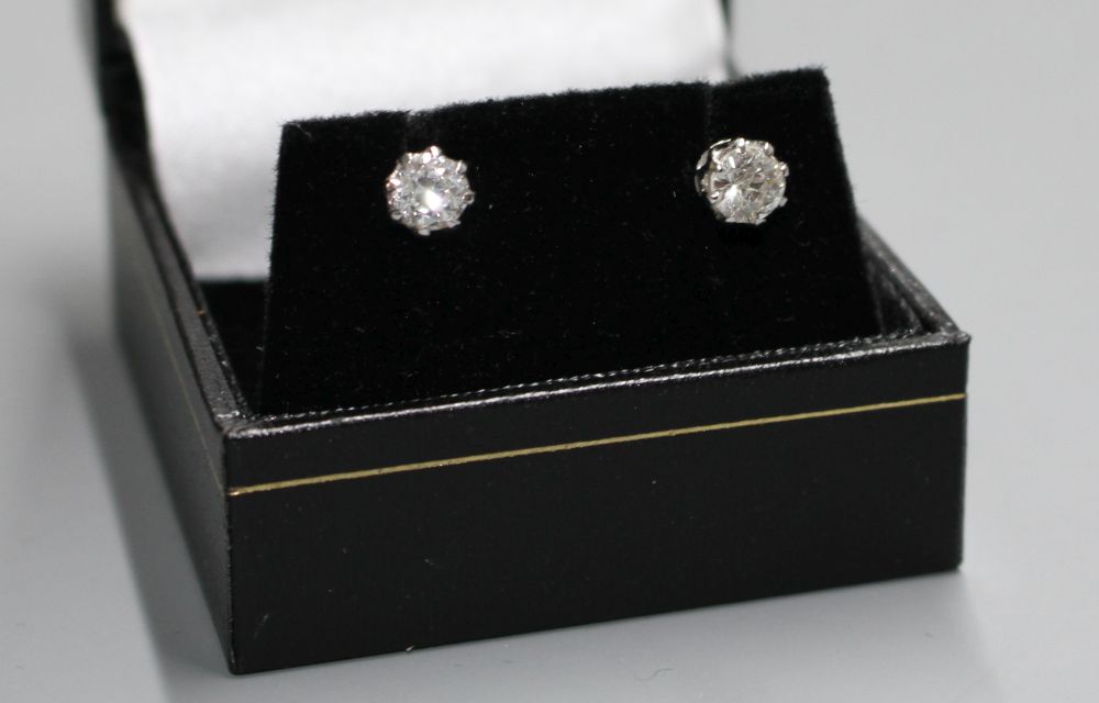 A pair of white metal and solitaire diamond ear studs,